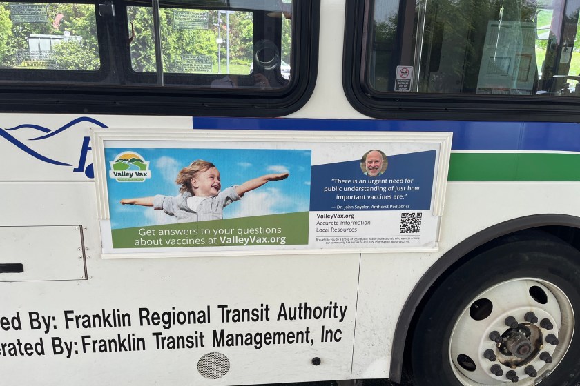 bus An advertisement on the outside of a public transit bus shows a child smiling with arms outstretched.