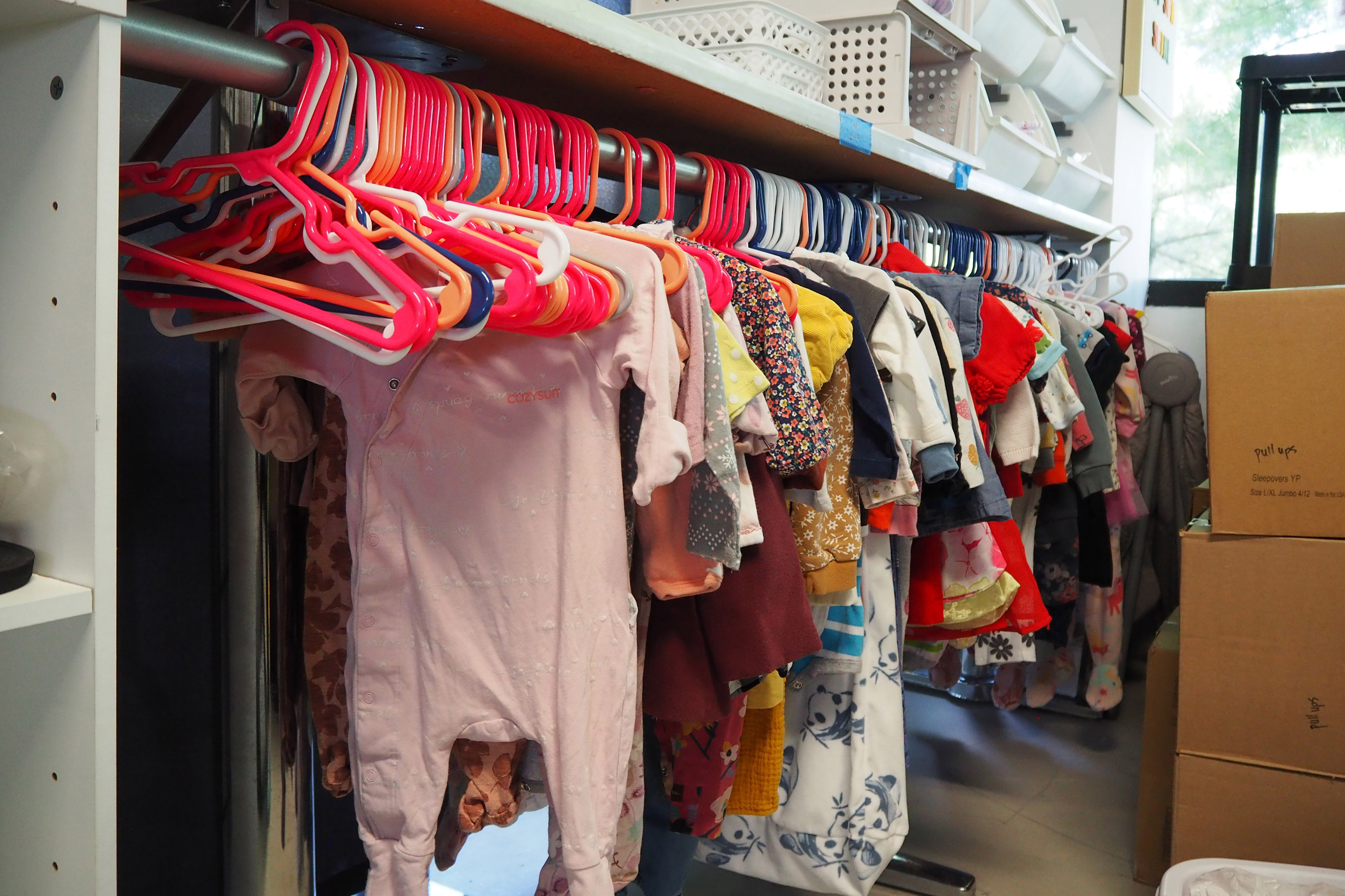 doulas-07-web-2 Baby clothing hangs on multicolored hangers on a clothing rack