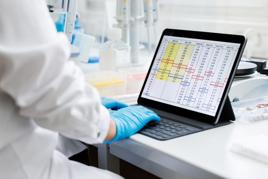 A photo of a clinical researcher in a laboratory working on a tablet.