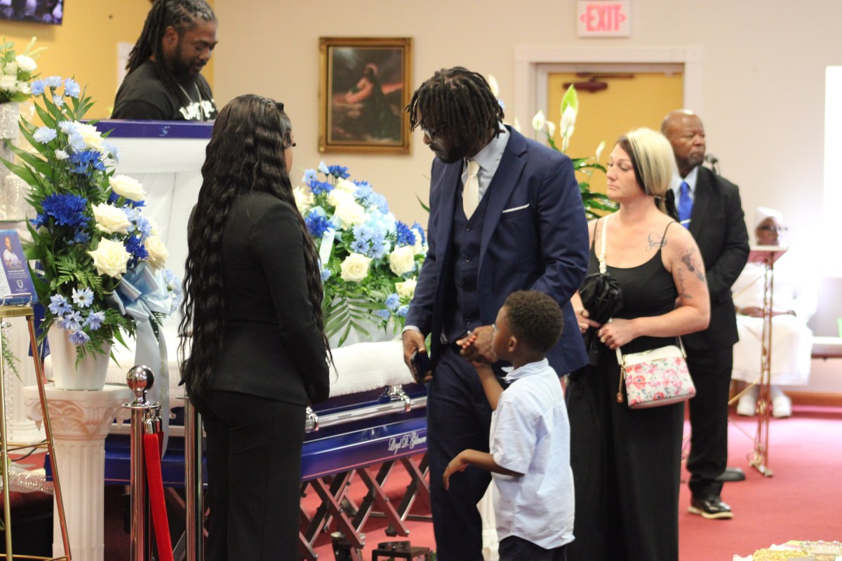 A man with his child stand beside an open casket.