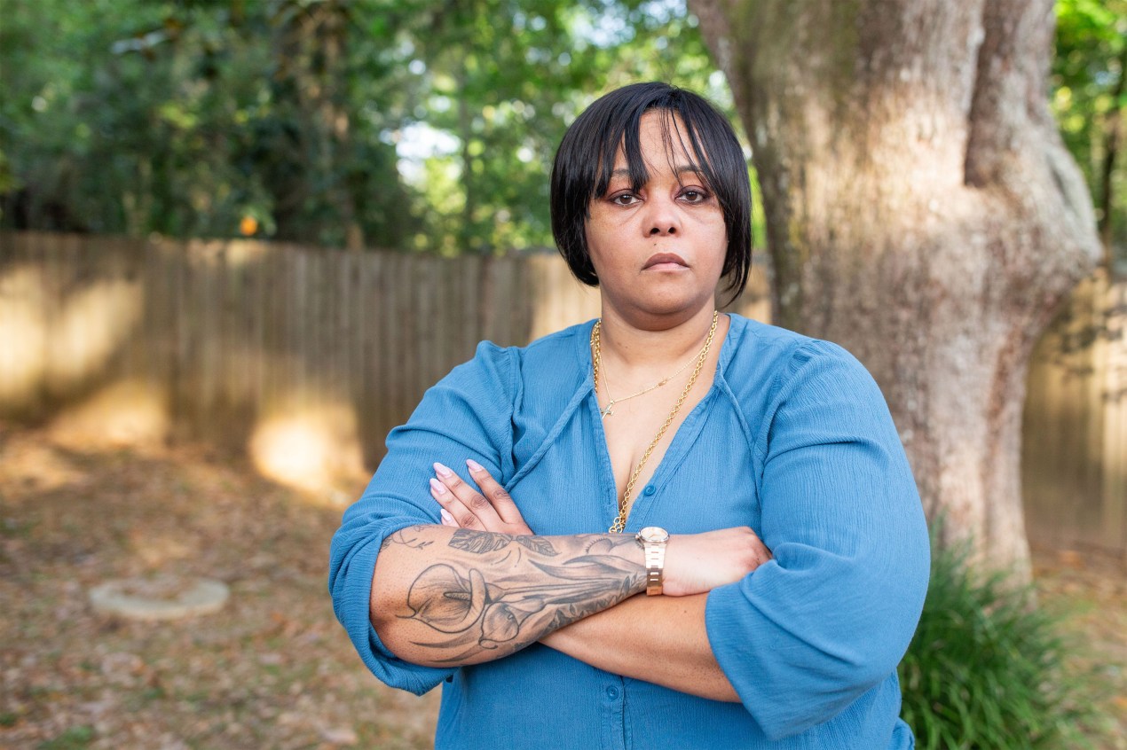 Alea Bates stands in her backyard with her arms crossed.