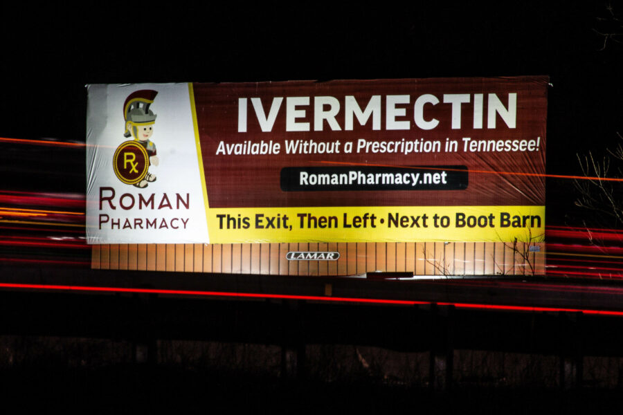 A night photograph of a billboard that shows an advertisement for ivermectin.