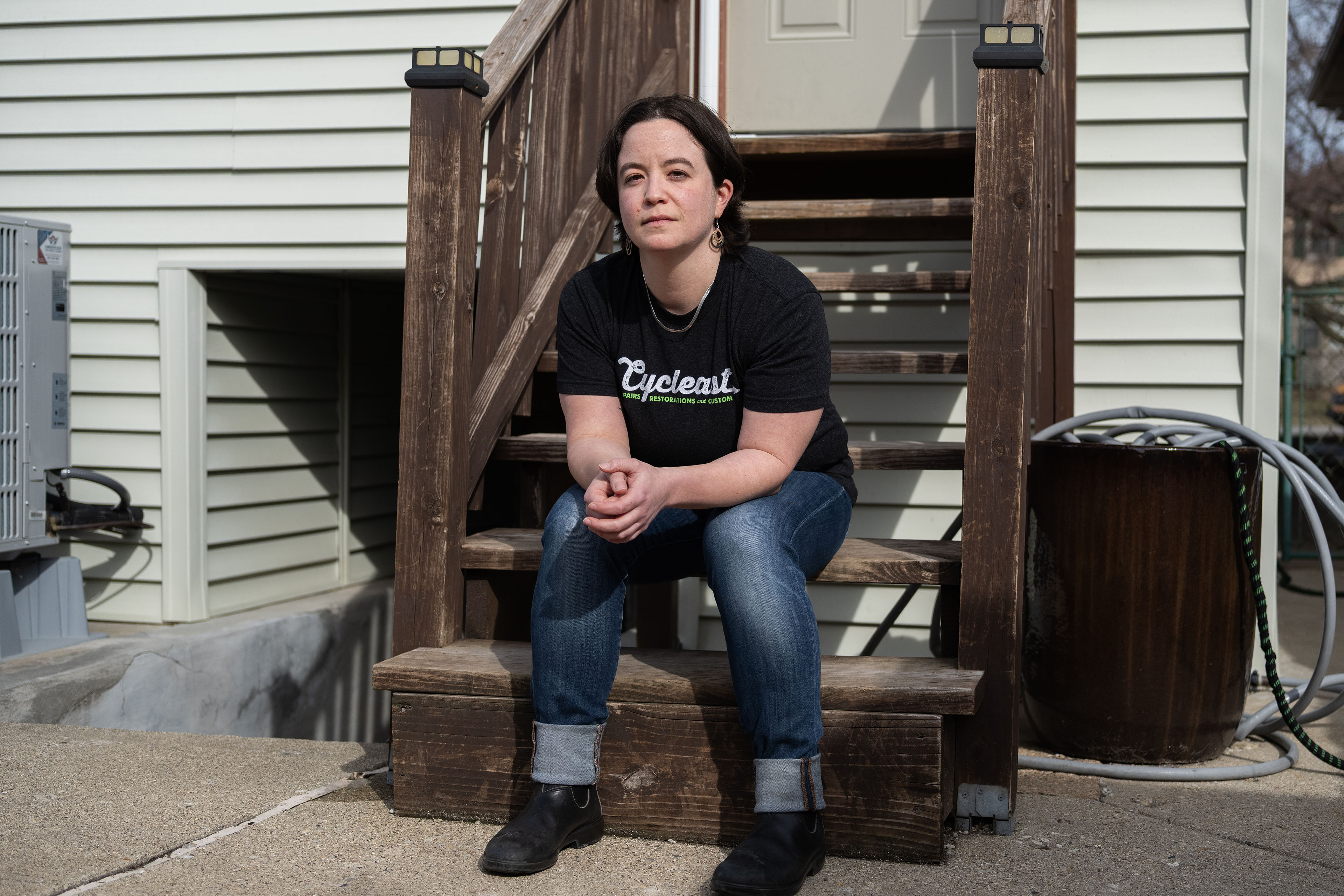 aiken_03 A person wearing a black T-shirt sits on wooden steps.