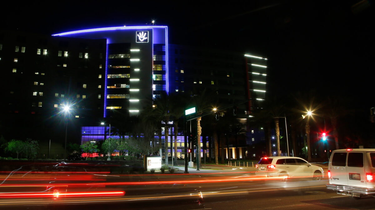 A photo of Phoenix Children's Hospital illuminated at night as cars drive by.
