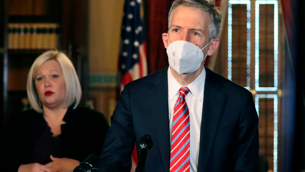 A photo of a man in a suit wearing a KN-95 mask at an official event.