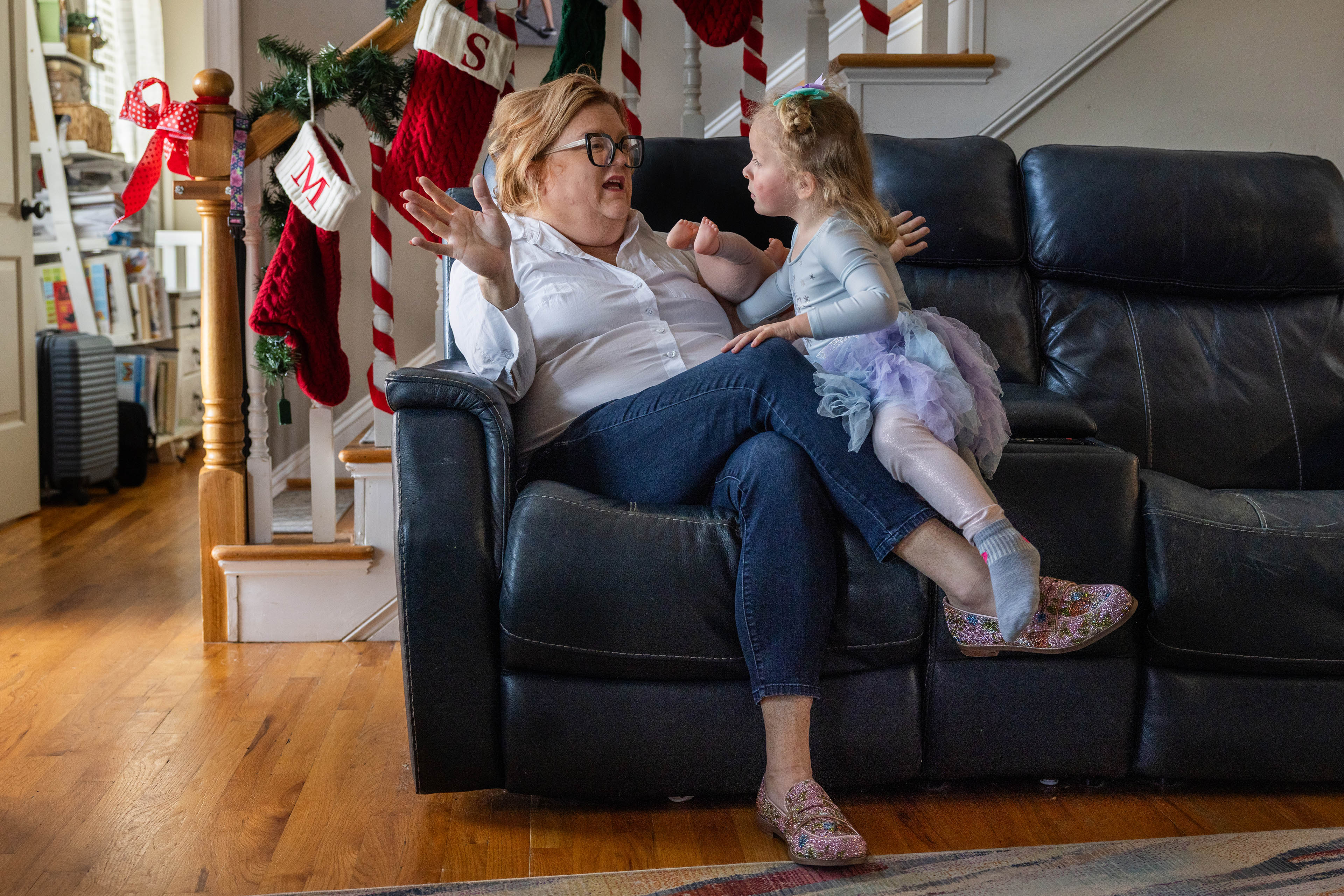 autism-medicaid_osborne_08 A mother sits with her 3-year-old daughter on a couch in their home. In the background are Christmas decorations.