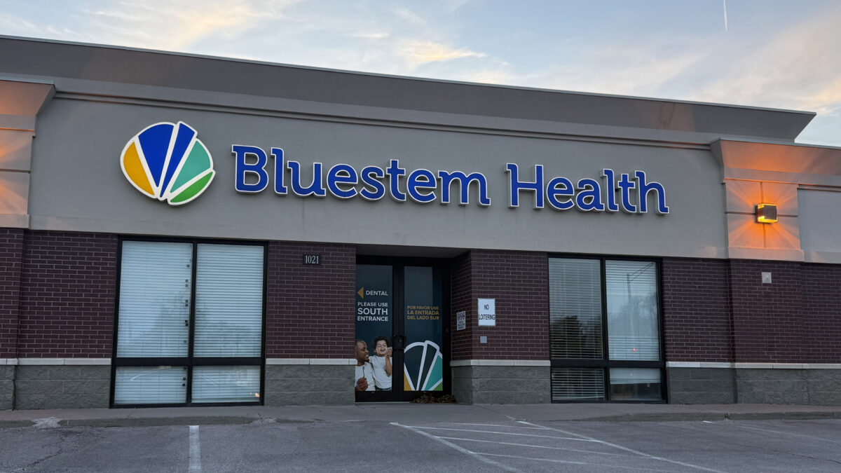 An exterior of a health clinic with a blue sign that reads, "Bluestem Health."