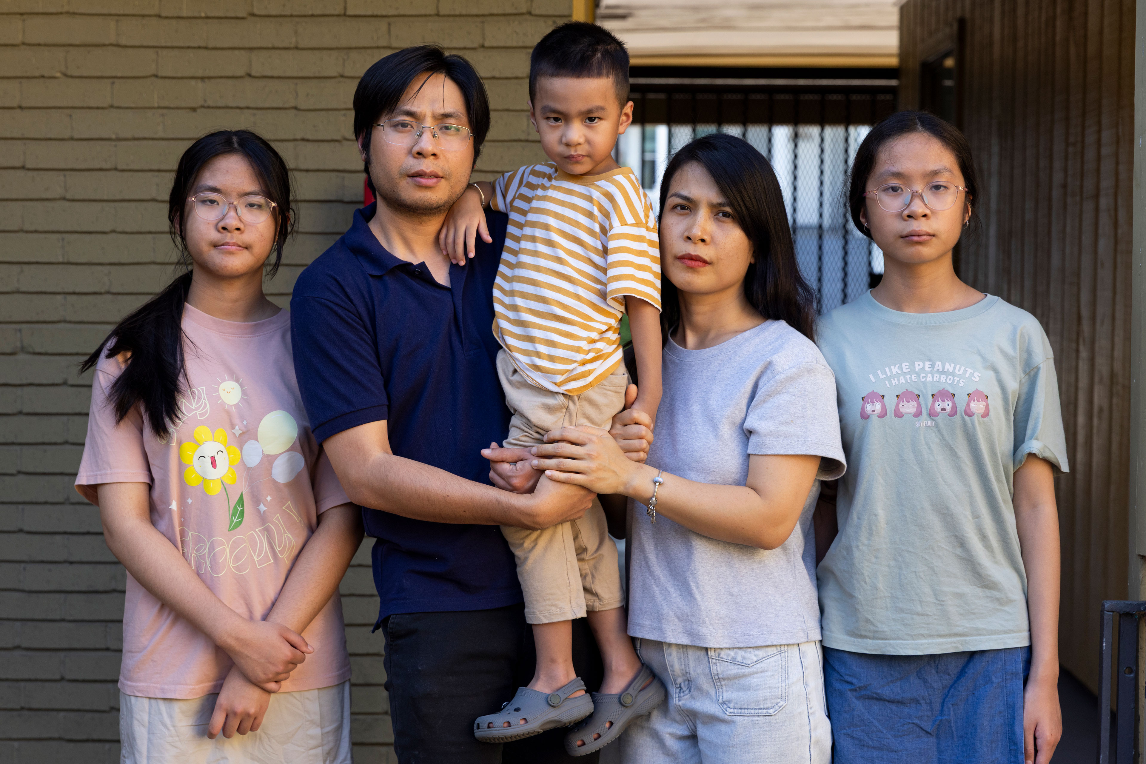 A family of five stand together outside a building.