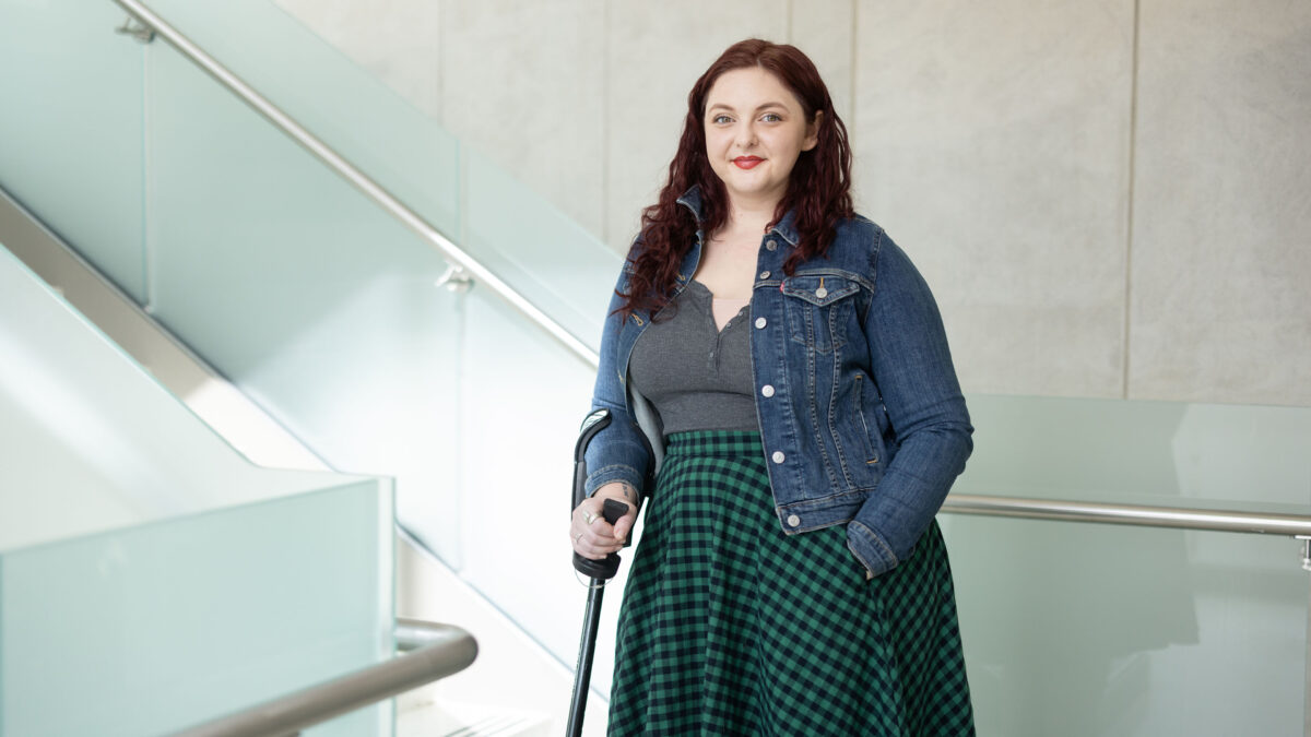 A portrait of a young woman leaning gently on a cane.