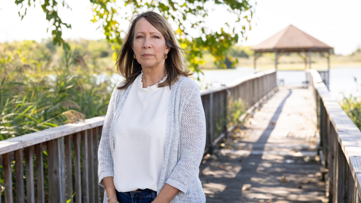 A photo of a woman standing outside on a dock by a gazebo.