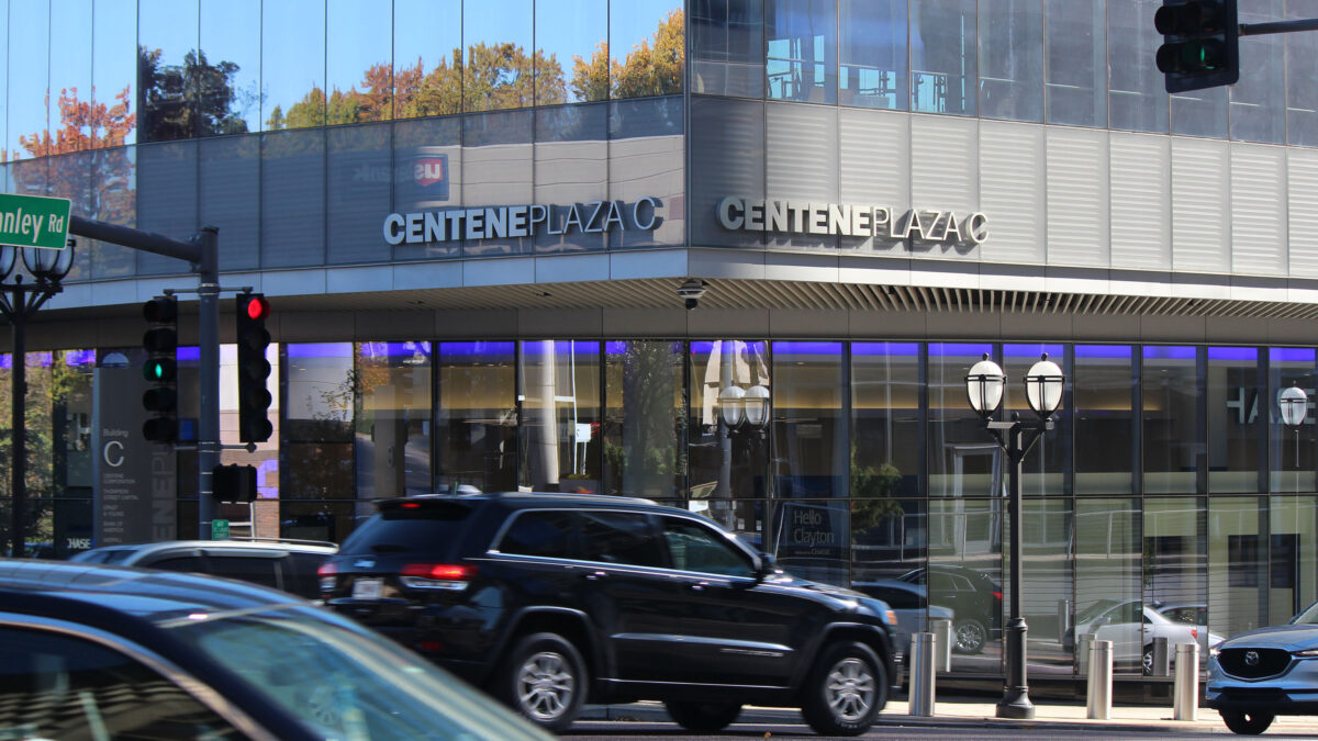 An exterior photograph of a modern office building in a metropolitan area. Cars are seen driving in front of the building labeled "Centene Plaza."