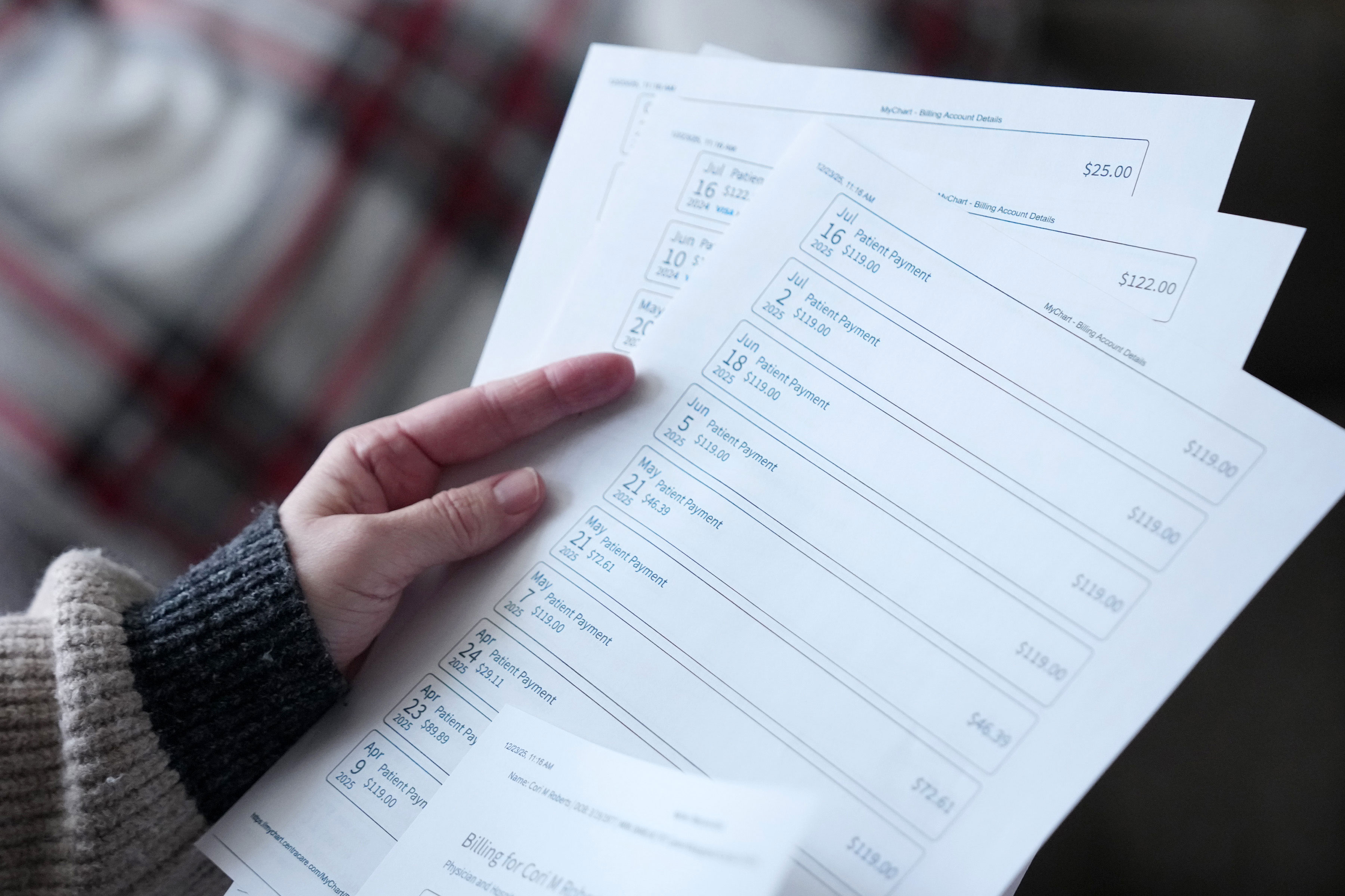 charity-care02_3600x2400web A hand holds at least four sheets of paper printed with the date and amounts of payments. There are 10 payments listed on the clearest page.