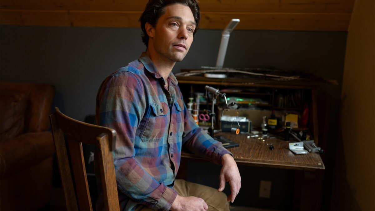 A photo of a man sitting at a desk indoors.