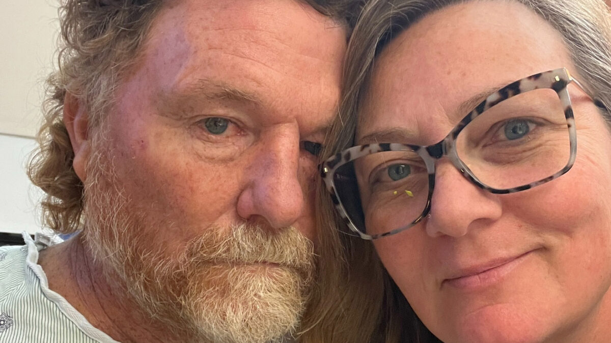 A photo of a husband and wife taking a selfie together indoors.
