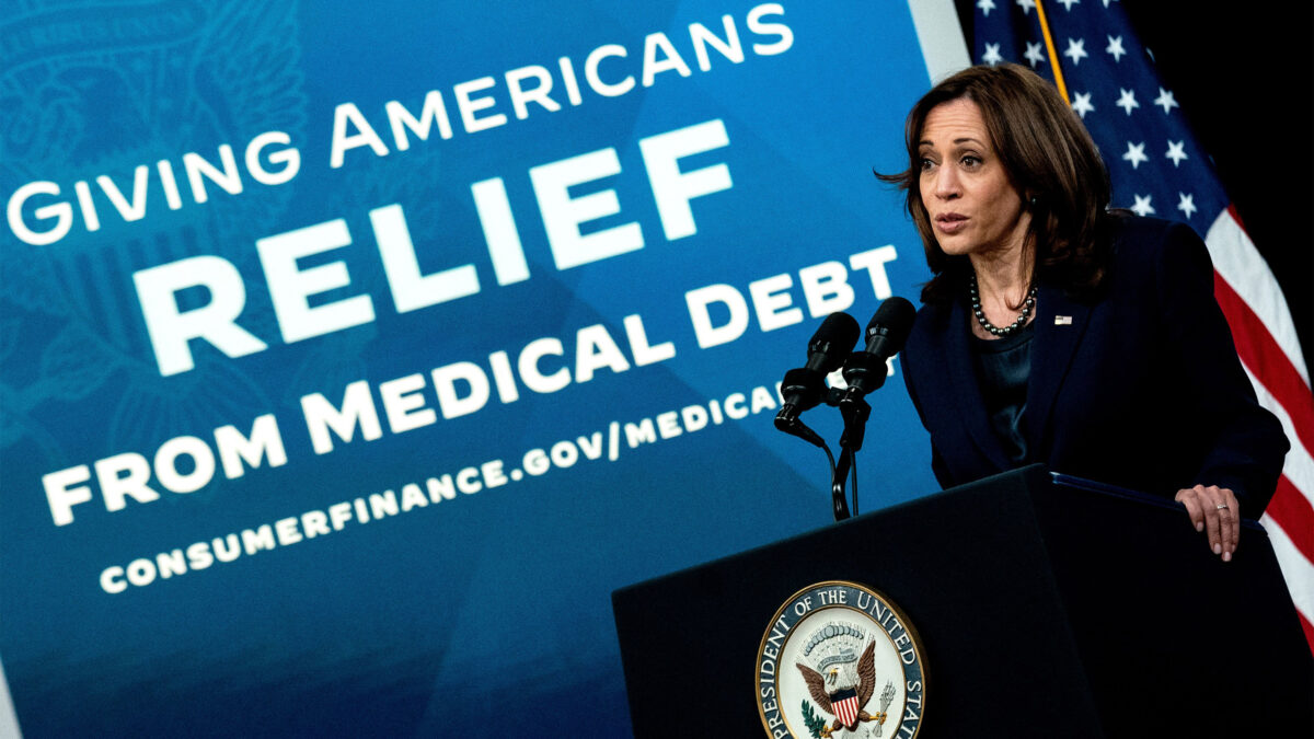 A photo of Kamala Harris speaking at a podium. Behind her is a large backdrop that reads "Giving Americans Relief From Medical Debt."