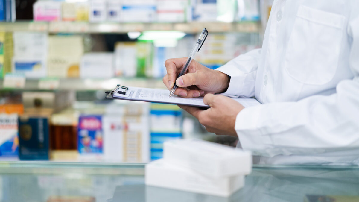 A photo of a pharmacist writing notes on a clipboard.