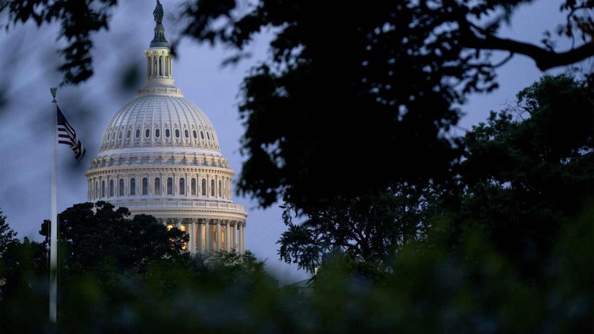 A photo of the U.S. Capitol from afar, framed by trees.