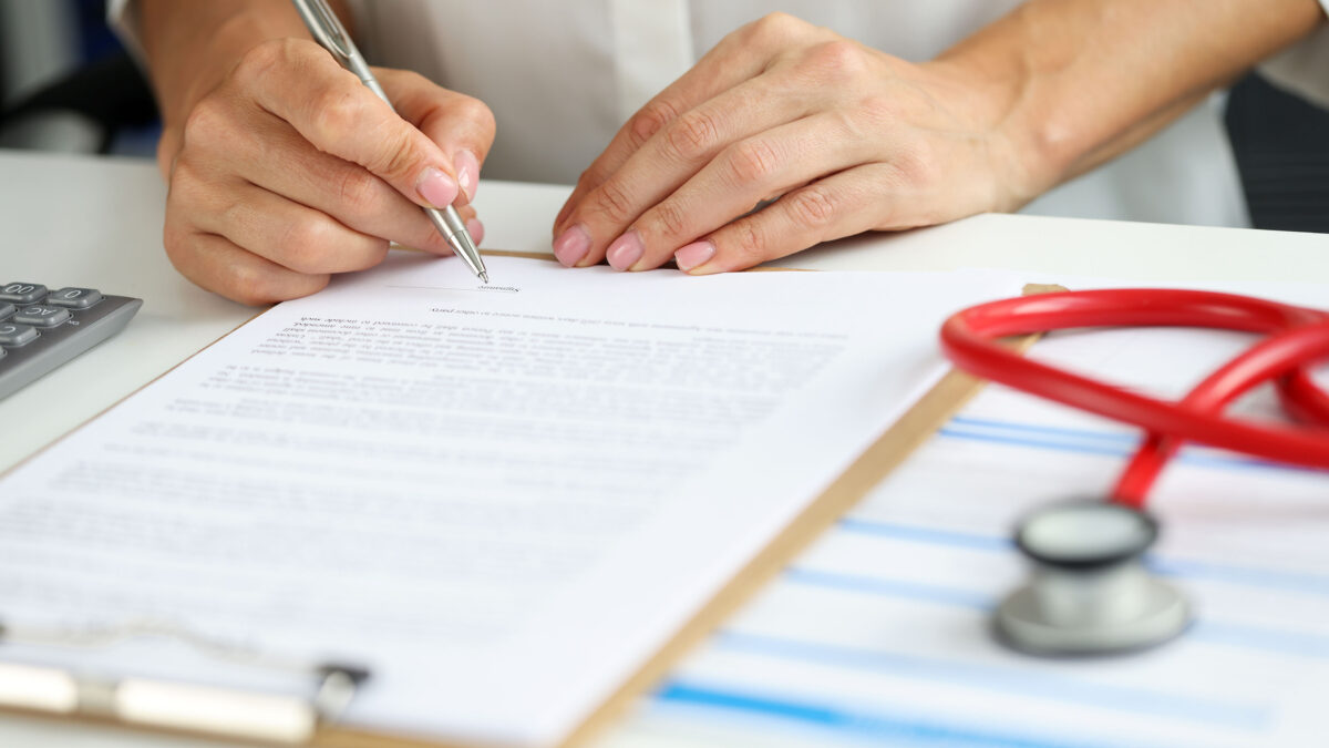 A close-up photo of a person writing on a clipboard.
