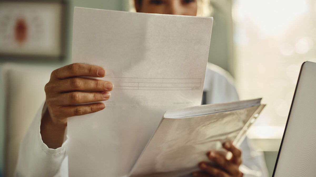 A photograph of a woman holding up a piece of paper. Her face is obstructed from view.