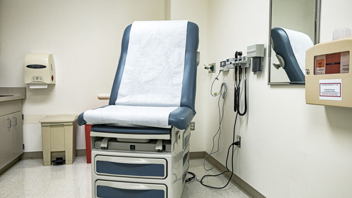 A doctor office examination room with the examination table/reclining chair in its most upright position.