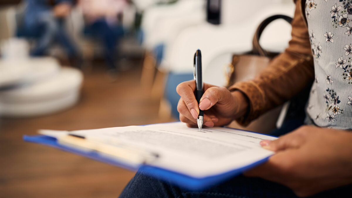 A photo of a woman in a medical office filling out a form.