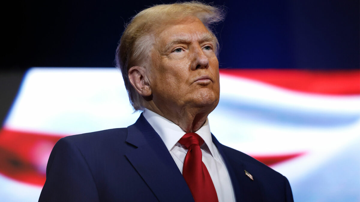 A photo of Donald Trump standing in front of a screen.