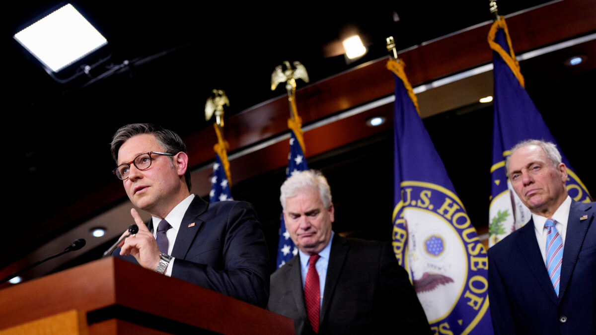 A photo of Mike Johnson standing at a podium with two men behind him: Tom Emmer and Steve Scalise.