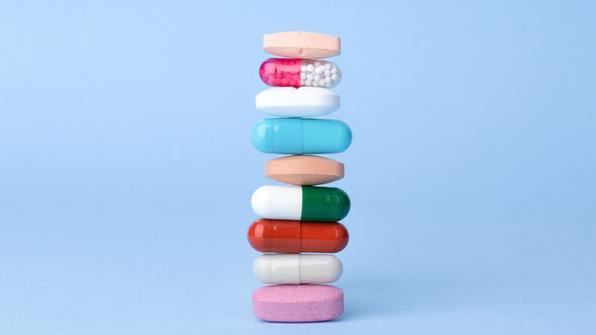 An up-close artistic photo of a stack of different multi-colored pills.
