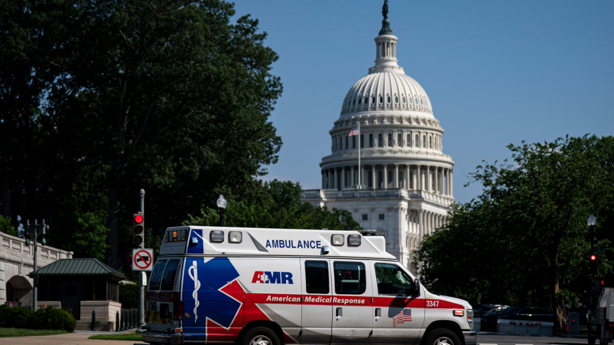 A photo of an ambulance driving by in Washington, D.C. The rotunda of the U.S. Capitol is prominent in the background.