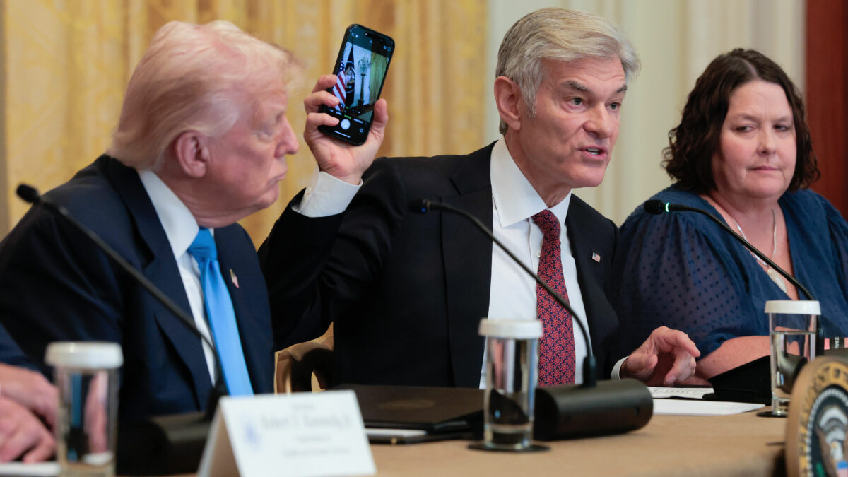 A photo of Mehmet Oz holding up a phone during a White House meeting about health care and technology.