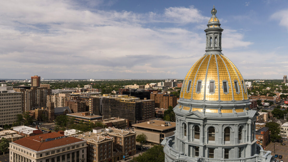An aerial view of the gilded dome atop the Colorado Capitol in Denver. The city of Denver is seen behind it.