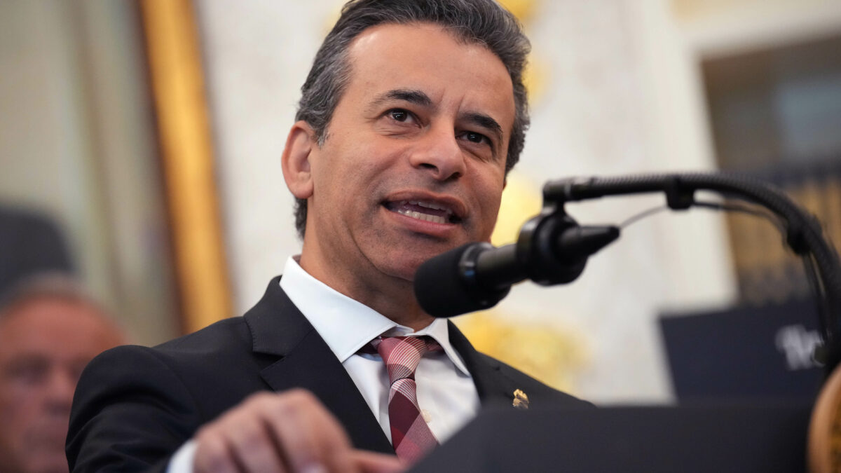 A close-up photograph of Marty Makary speaking into a microphone at a podium.