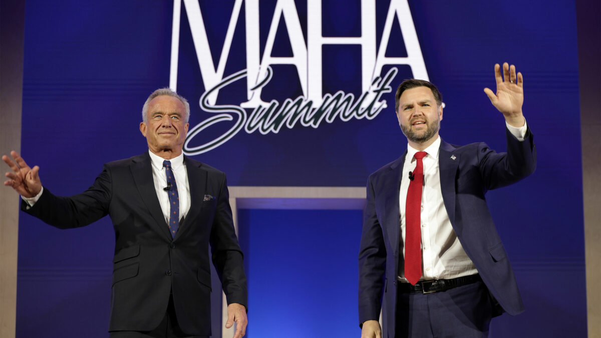 A photo of Robert F. Kennedy Jr. and JD Vance waving to an audience at a conference in D.C. Behind them is a sign reading "MAHA Summit."