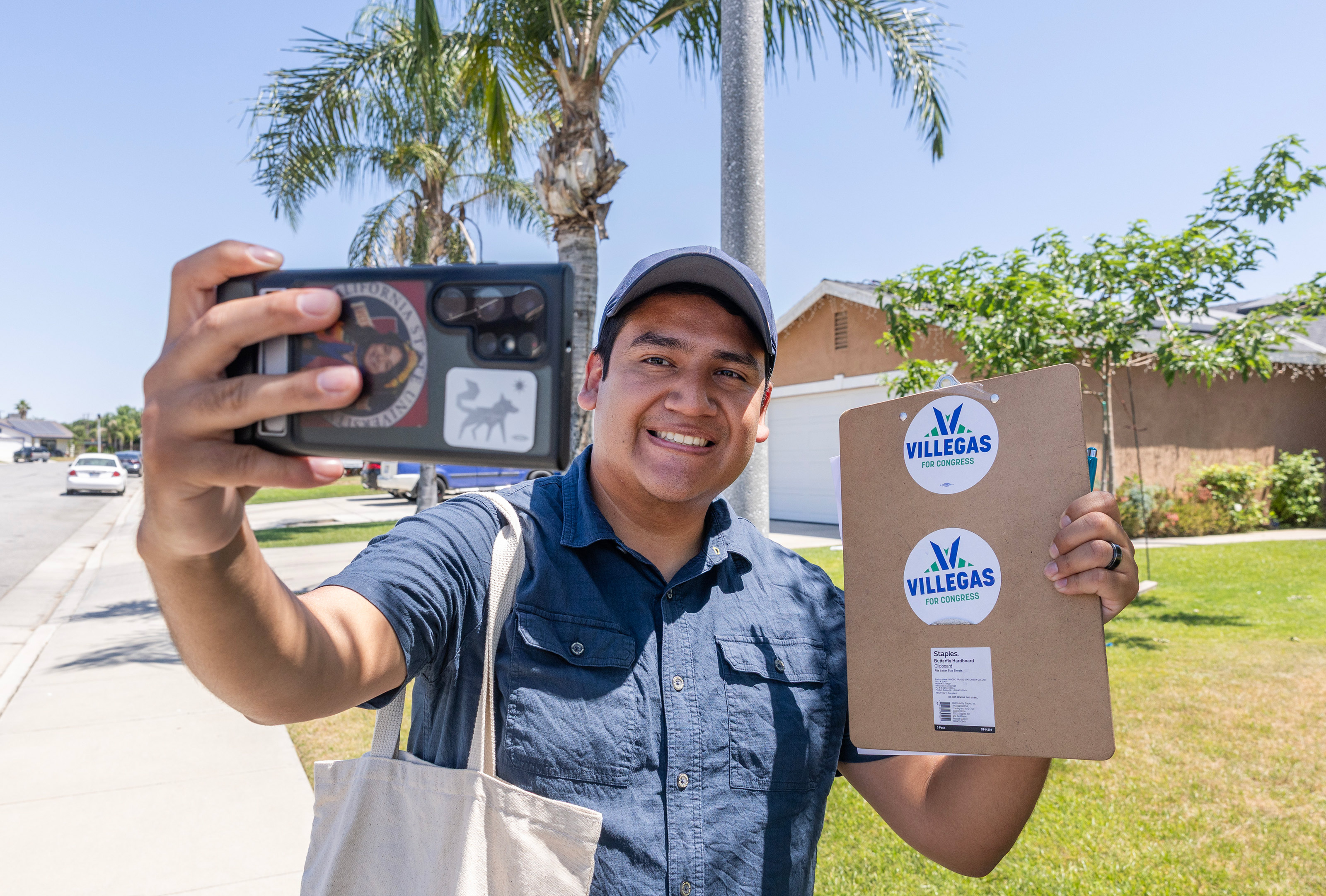 gettyimages-2277367912 A photo of Randy Villegas taking a selfie while holding up campaign stickers.