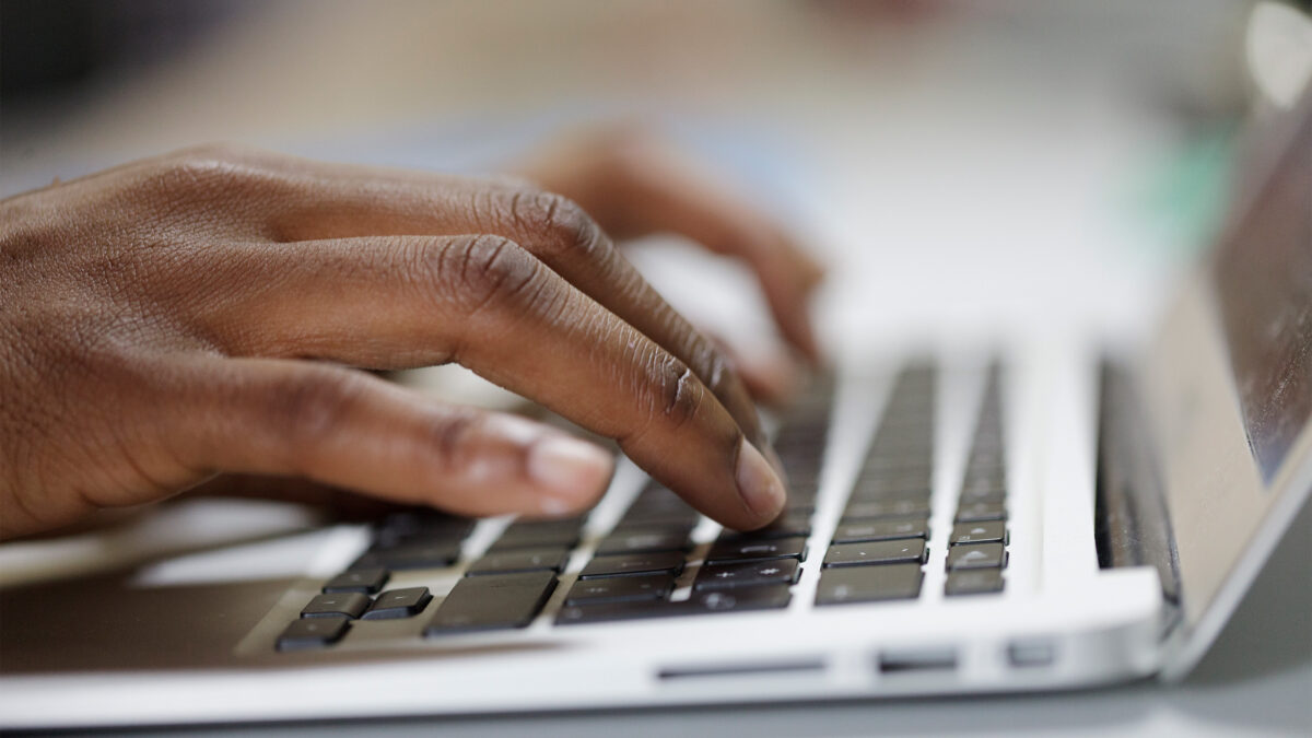 A photo of hands typing on a laptop keyboard.