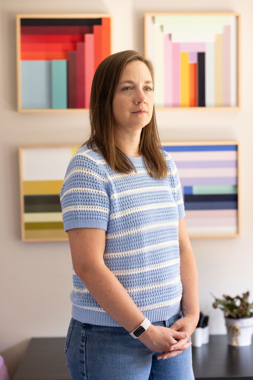 halver_23 A photo of Stephanie Halver standing in her living room. Four colorful prints are seen hanging on the wall behind her.