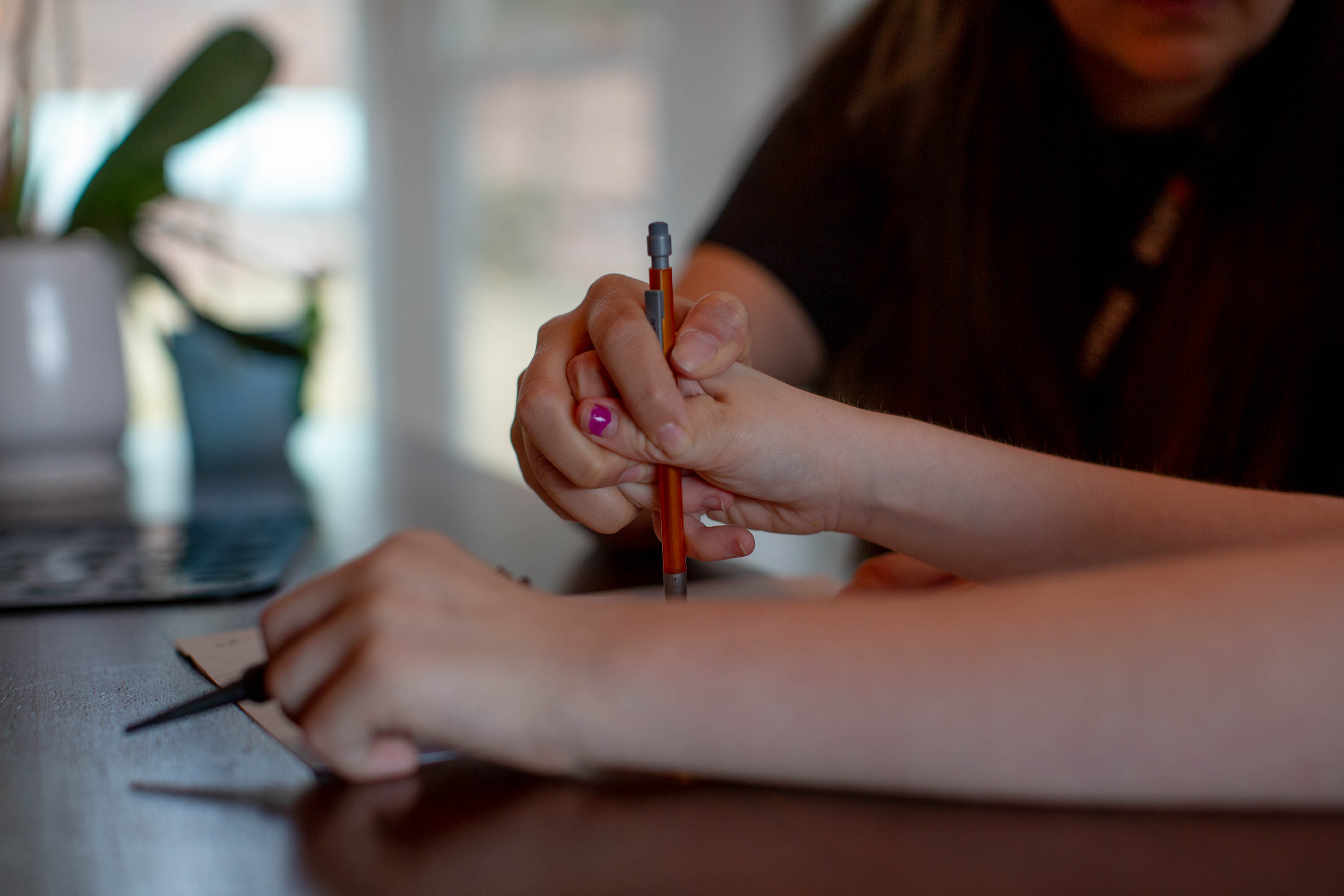 immigrant-caregivers-014 A woman holds the hand of a girl as she writes with a mechanical pencil