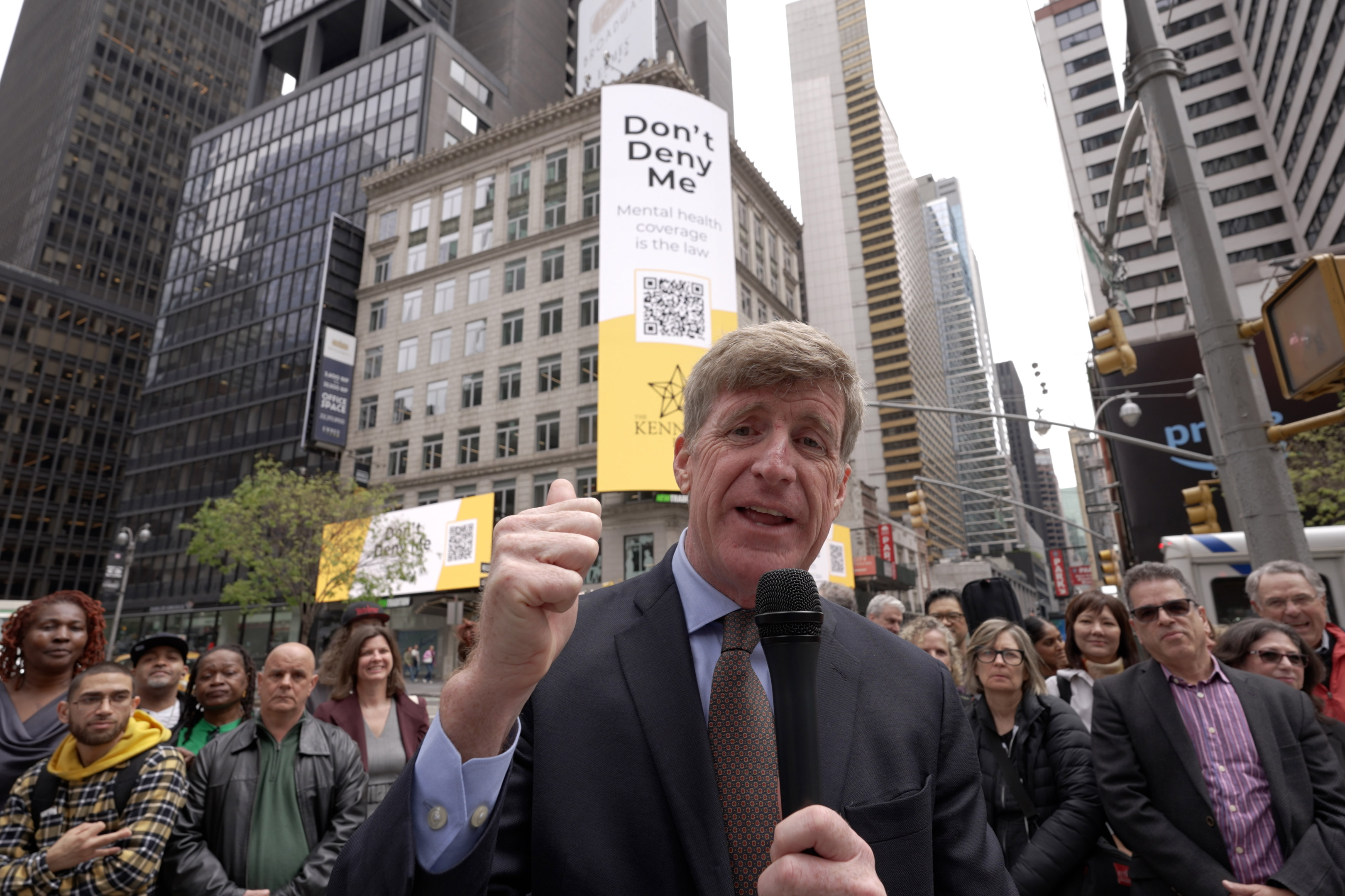 kennedy-resized A photo of a man holding a microphone, speaking to the camera, with a crowd behind him.
