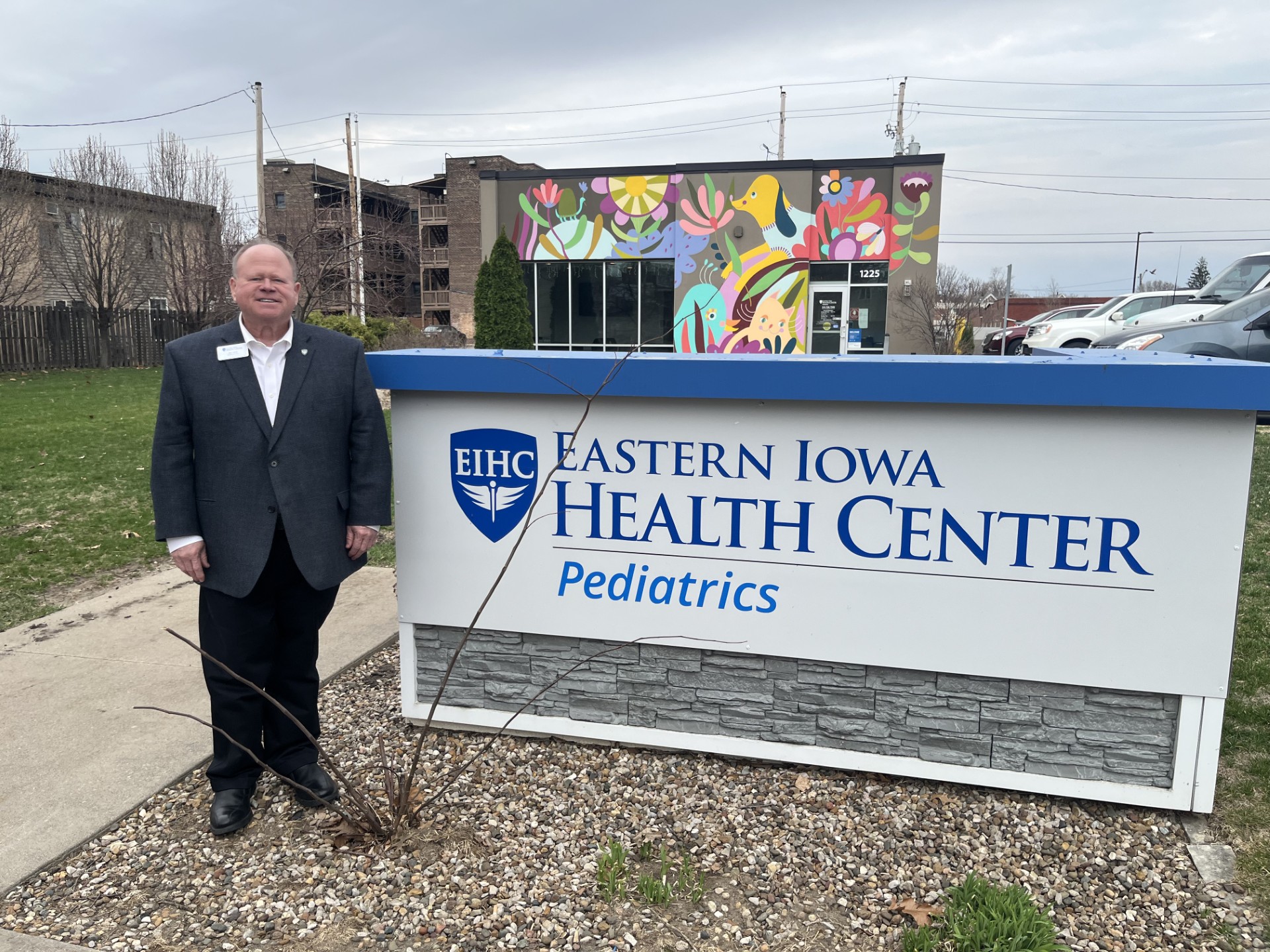 A man stands next to a sign that reads, "Eastern Iowa Health Center: Pediatrics."