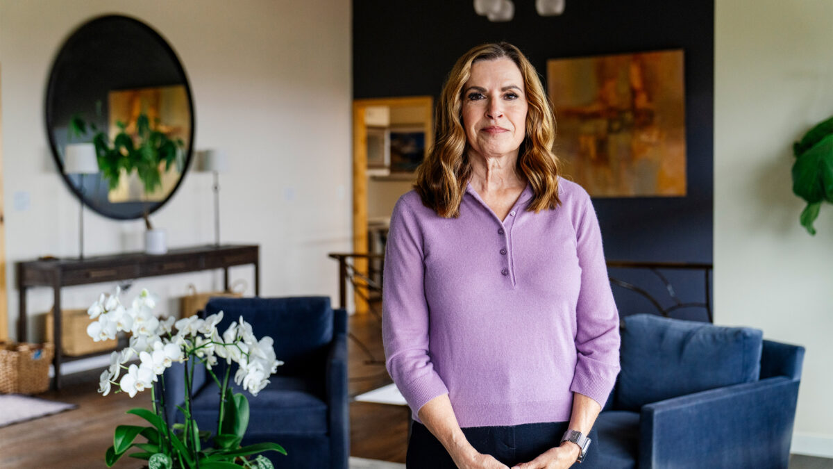 A woman stands in her living room.