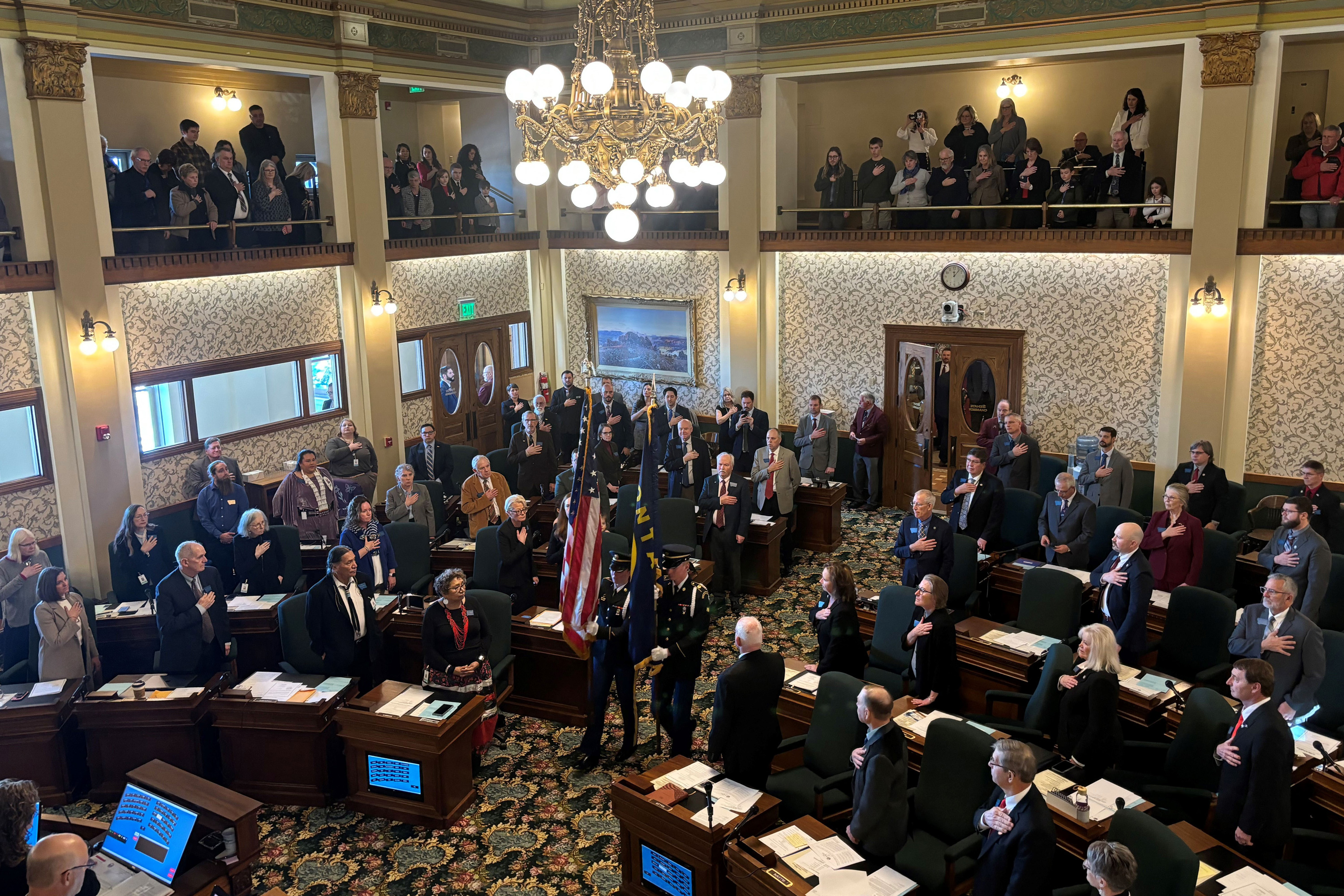 montanalegislature_1 A photo of Montana state senators standing as a two flagbearers carry a U.S. and Montana flag into the room.