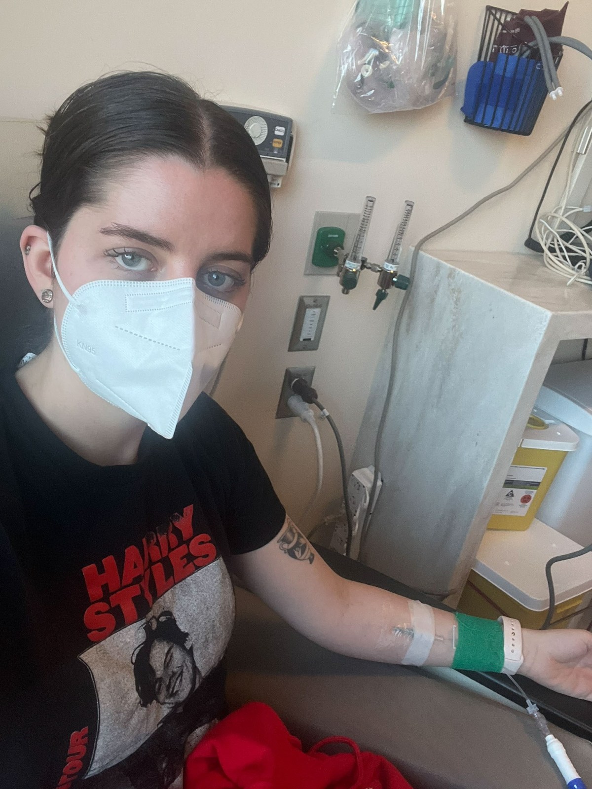 A woman wearing a mask with an IV in her arm