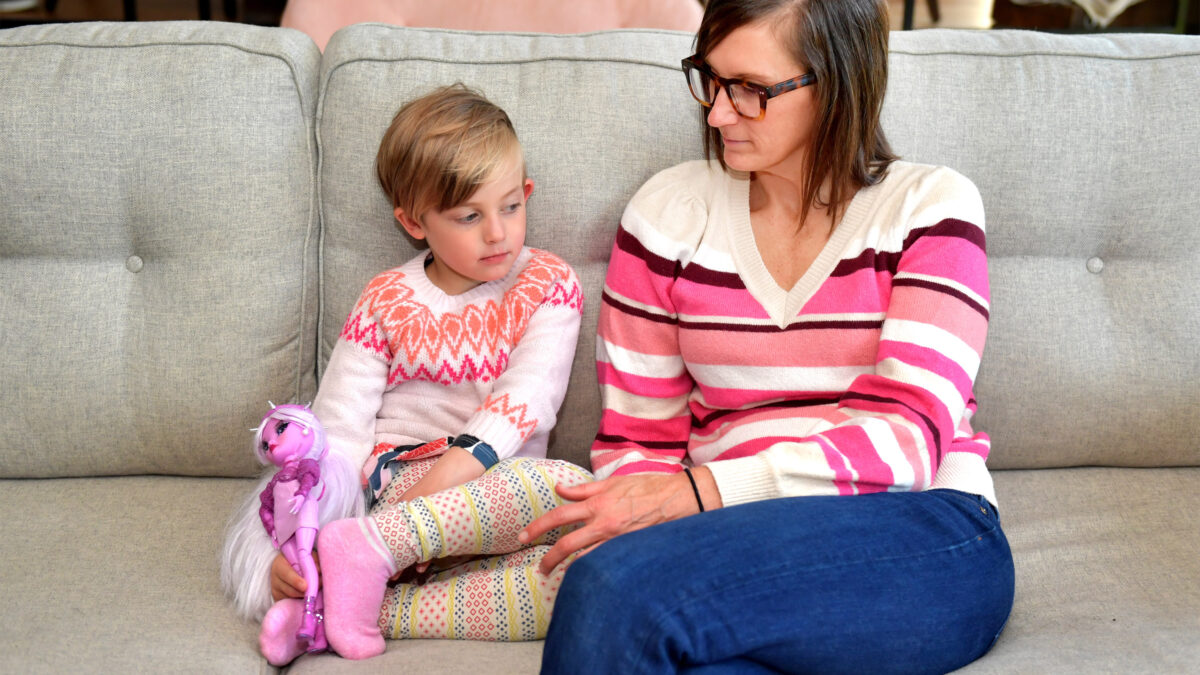 A photo of a mother and daughter sitting together on the sofa.