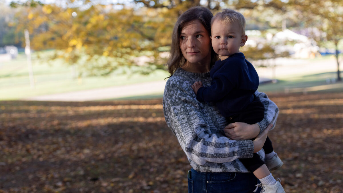 A photo of a woman holding her toddler outside.