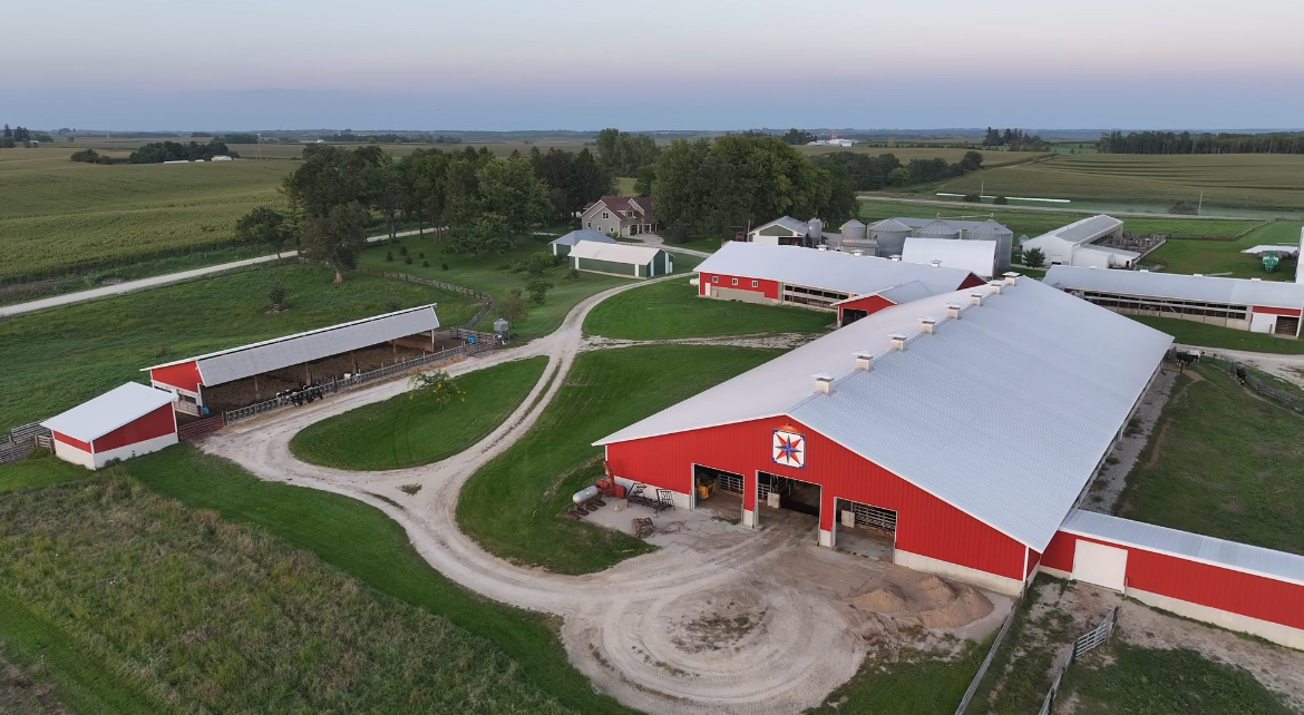 An aerial view of a farm with a red barn and several buildings around it.