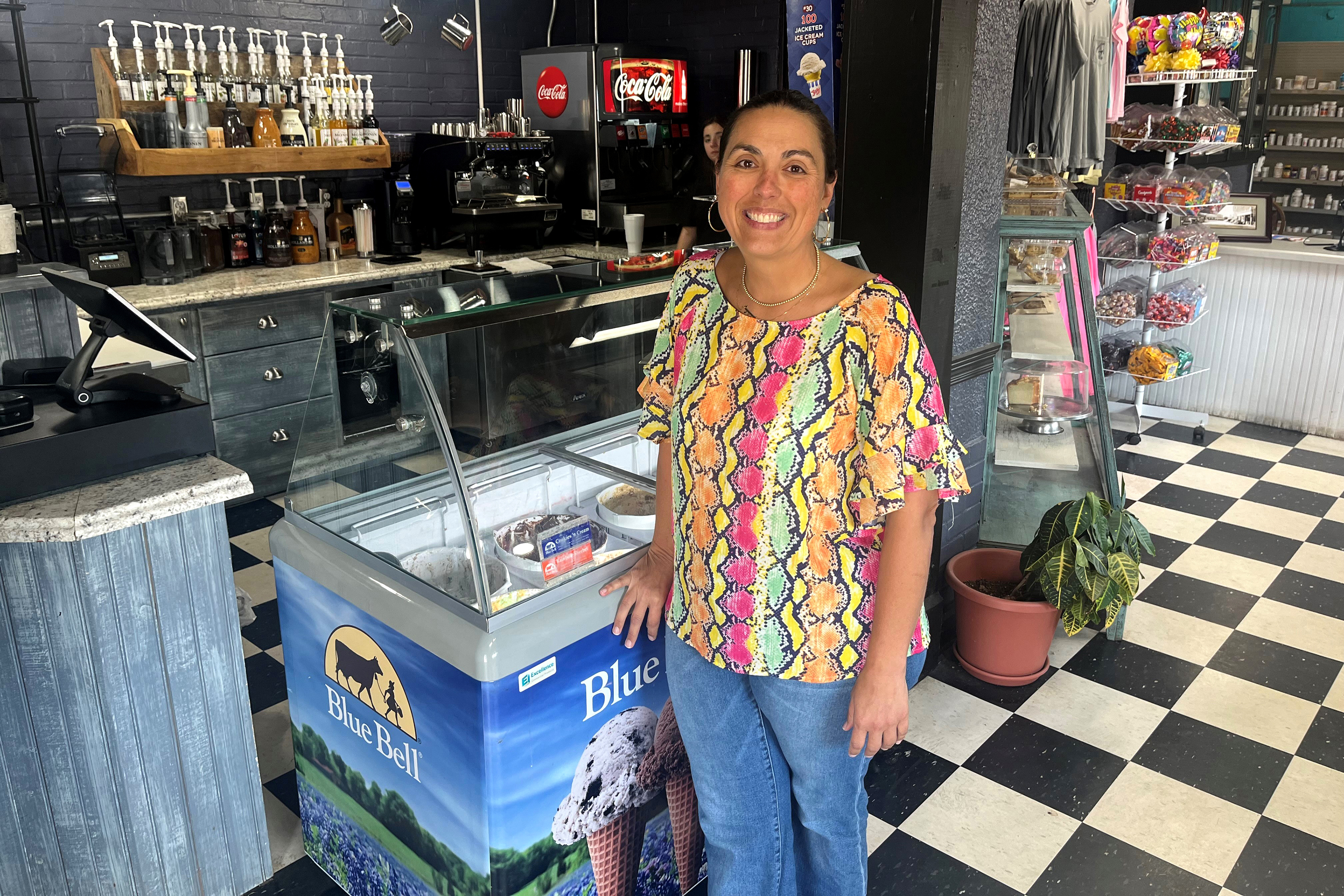 pbm-georgia-03 Nikki Bryant, a woman with brown hair pulled back in a ponytail, smiles for a photograph inside her family pharmacy.
