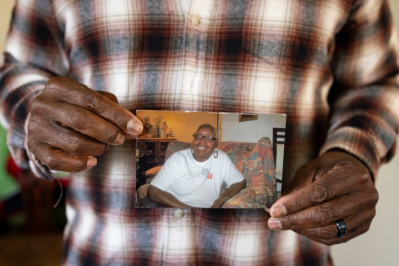 reit-leslie-adams-08-3840 A man holds a paper photograph of a woman in his hands for a photo