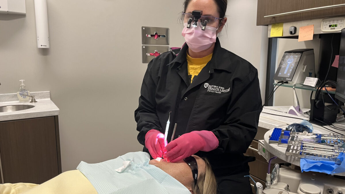 A dental hygienist works on a patient in a dental chair.