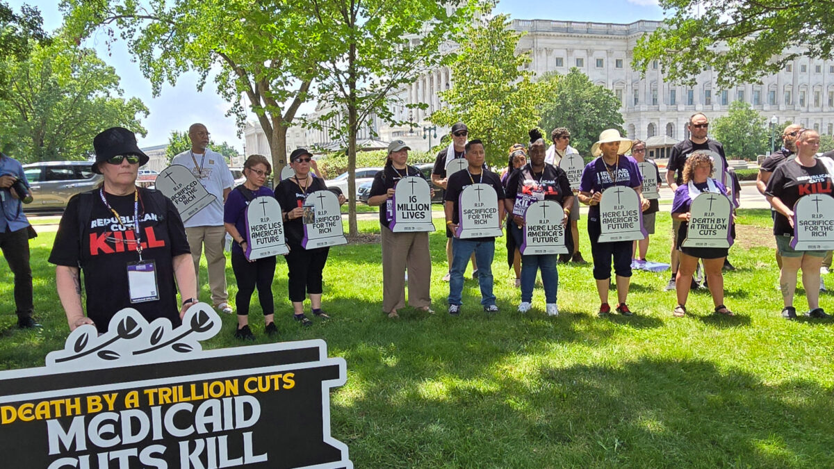 A group of protesters stand holding signs. One large sign reads, "Death by a trillion cuts: Medicaid cuts kill." Others hold signs shaped like tombstones that read, "Here lies America's future," and "R.I.P. Sacrificed for the rich."